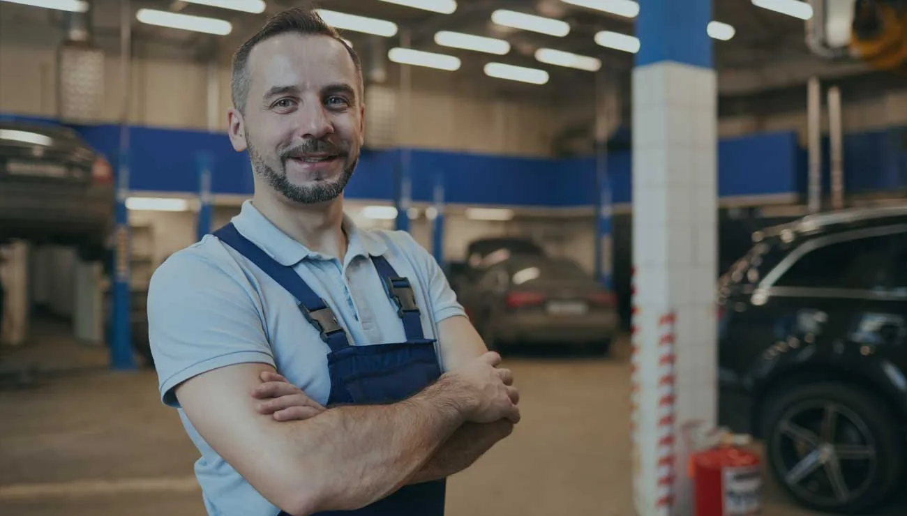 Mecánico con uniforme gris dentro de un taller automotriz