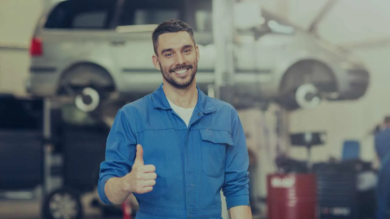 Mecánico sonriente dentro de un taller automotriz